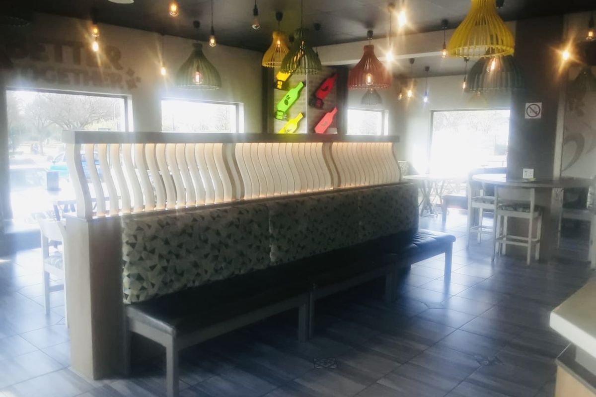 A commercial dining or lounge area featuring built-in booth seating, modern pendant lighting, and tiled flooring with large windows providing natural light.