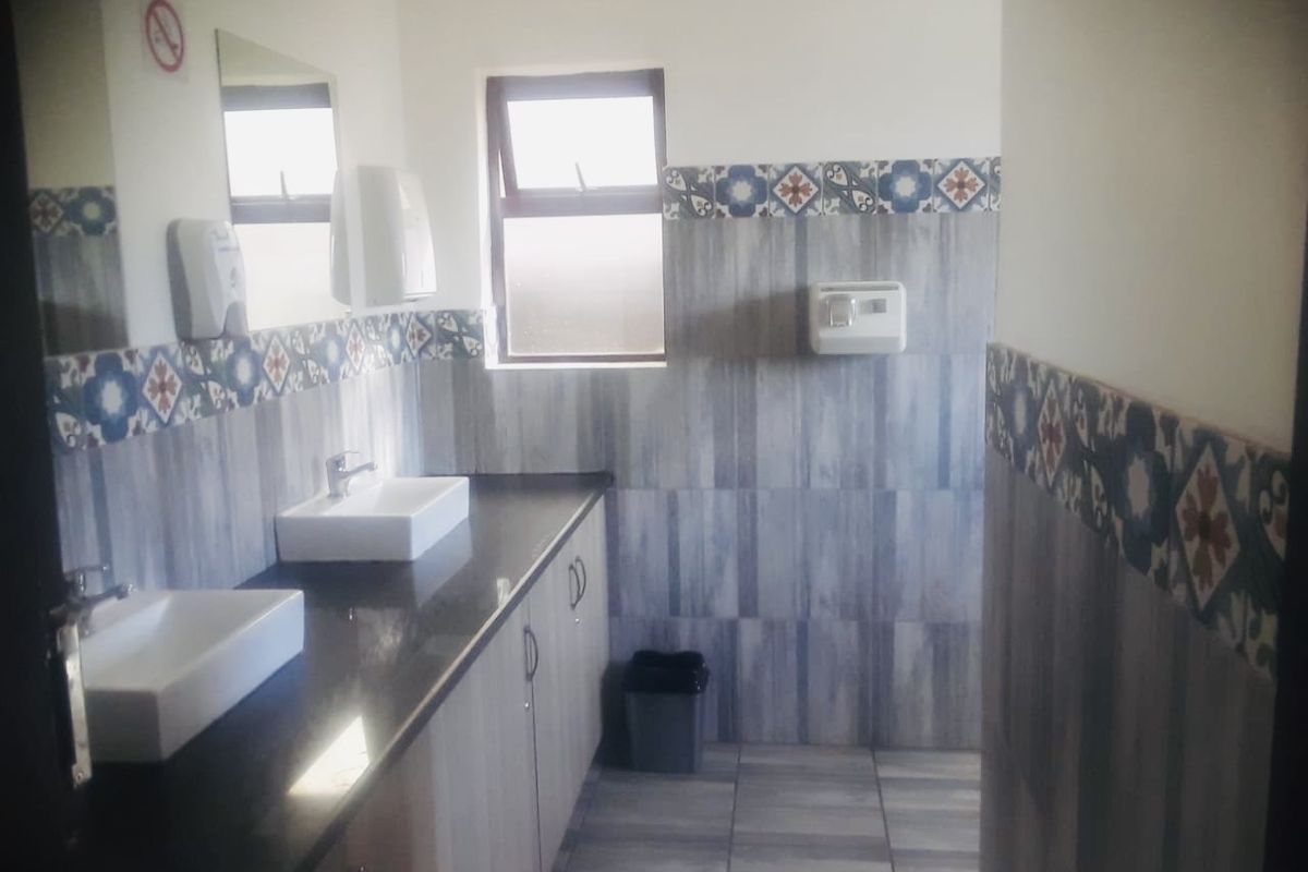A clean, functional bathroom featuring a double vanity with vessel sinks, granite countertops, and decorative tiled wall accents.