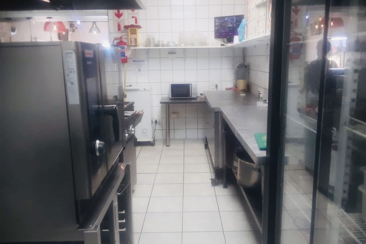A functional commercial kitchen space featuring stainless steel work surfaces, tiled finishes, and integrated commercial cooking equipment.
