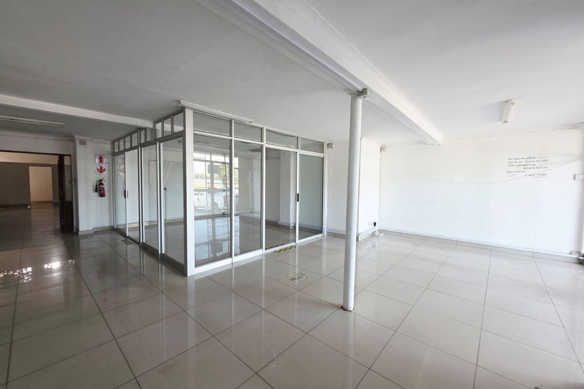 Open-plan office space featuring ceramic tiled flooring, a central support column, and glass-partitioned private office areas.
