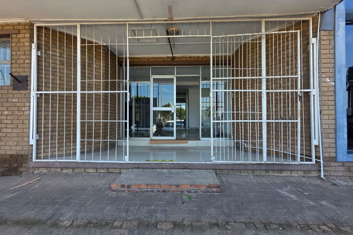 Front entrance of a commercial property featuring a brick facade, glass door, and protective security gate.