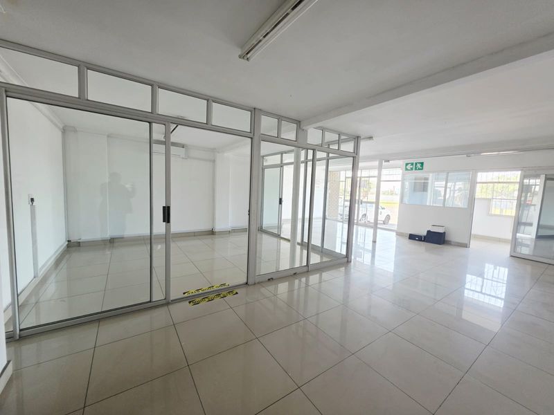 Open-plan office space featuring modern aluminium-framed glass partitions, tiled flooring, and bright, functional lighting, suitable for a professional business environment.
