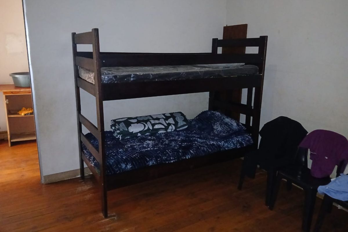 A bedroom featuring wooden flooring and plain walls, currently furnished with a bunk bed.