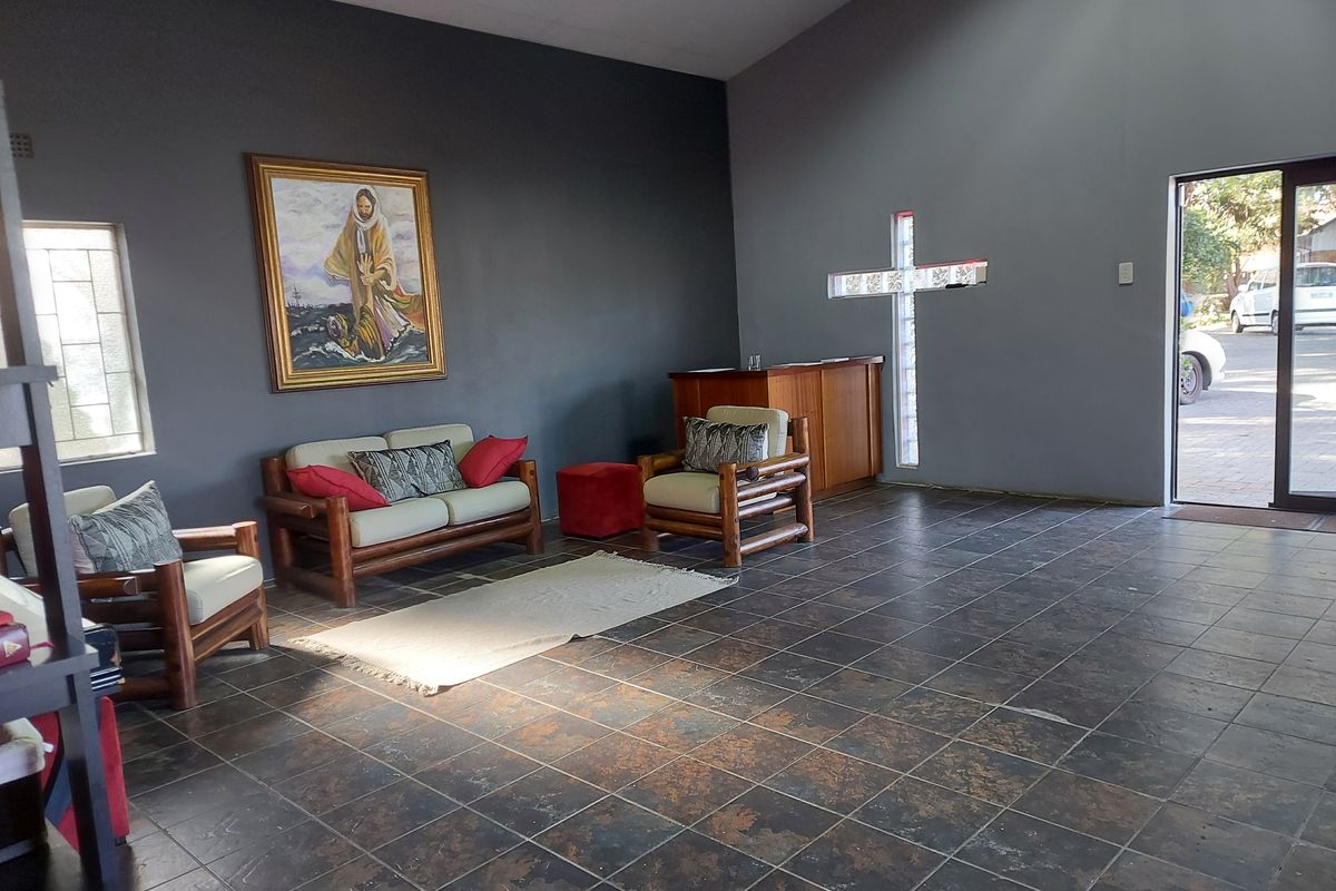 Spacious commercial interior featuring dark tiled flooring, a unique cross-shaped glass block window, and a built-in wooden service counter.