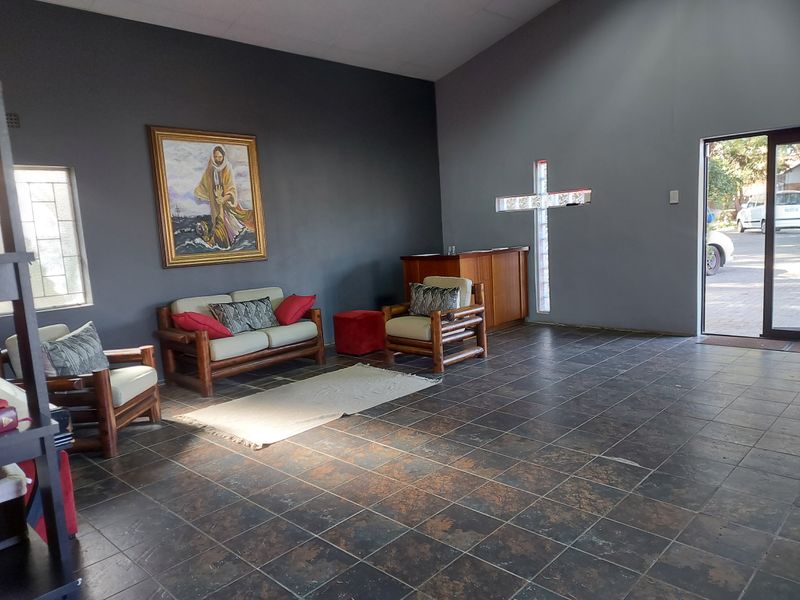 Spacious commercial interior featuring dark tiled flooring, a unique cross-shaped glass block window, and a built-in wooden service counter.