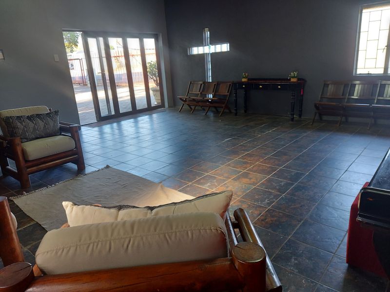 A spacious interior area featuring dark tiled flooring, a unique cross-shaped glass block feature window, and large sliding doors providing natural light.