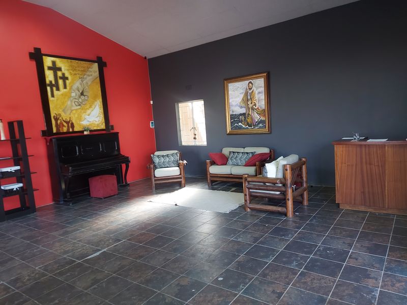 A spacious commercial living area featuring dark tiled flooring, contrasting red and grey walls, and a built-in wooden service counter.