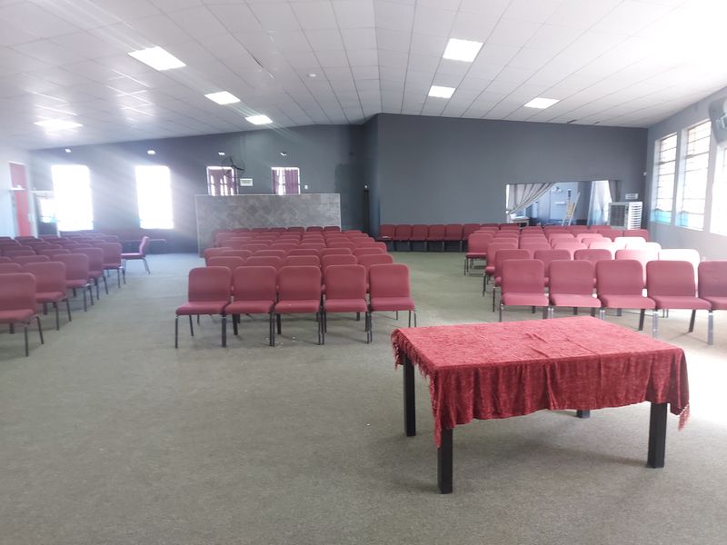 Spacious commercial hall featuring a suspended ceiling with recessed lighting and a tiled feature wall, suitable for events or meetings.