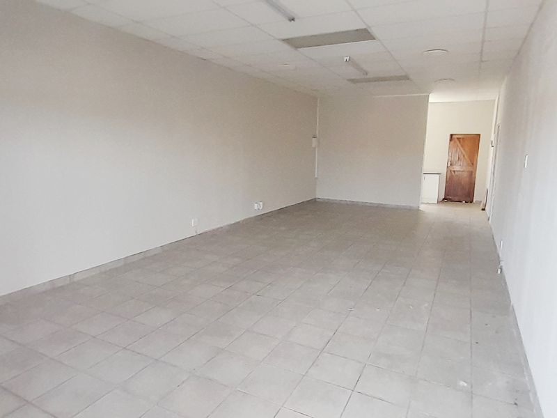 An empty, open-plan retail space featuring tiled flooring and a suspended ceiling, suitable for various commercial business applications.