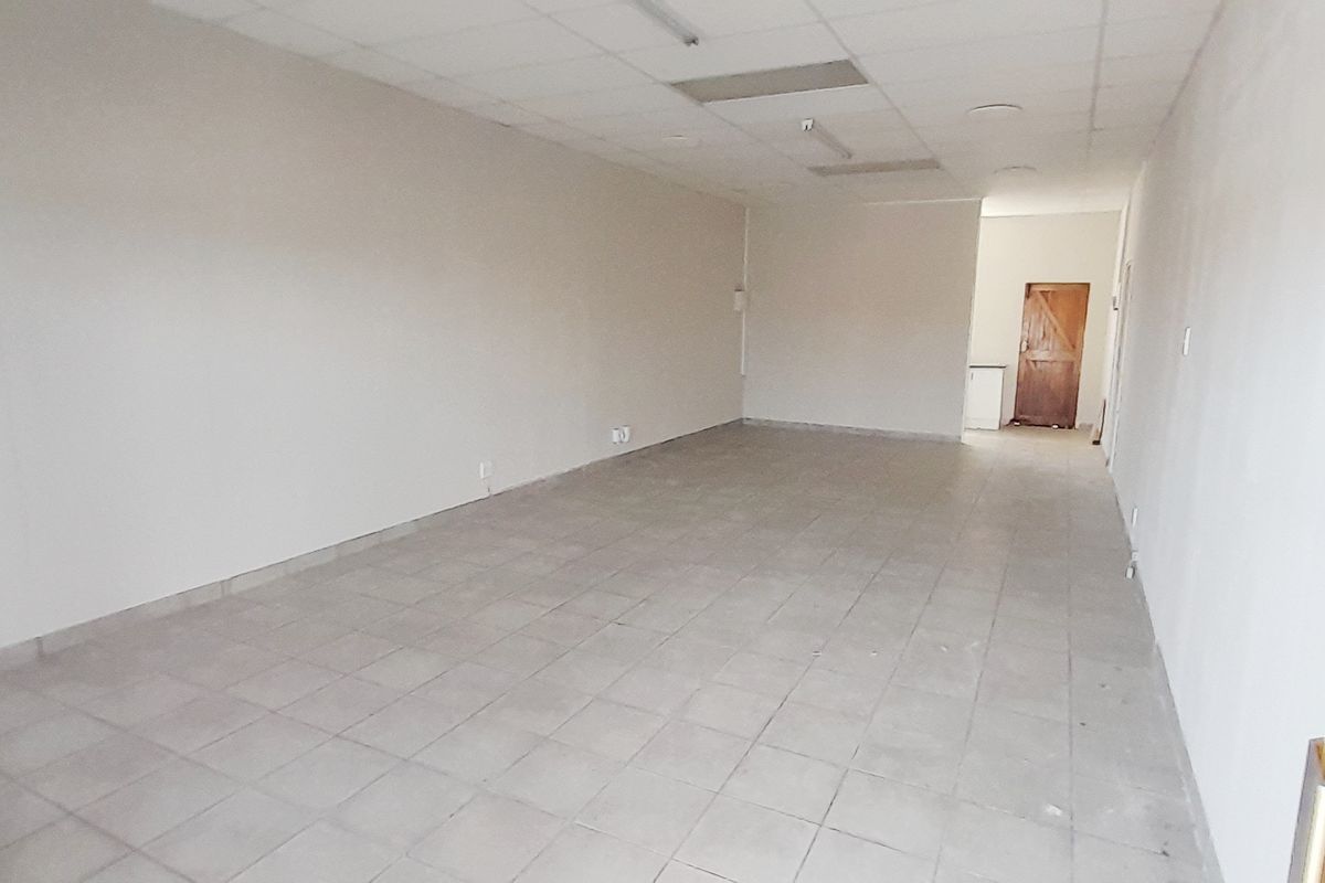 An empty, open-plan retail space featuring tiled flooring and a suspended ceiling, suitable for various commercial business applications.