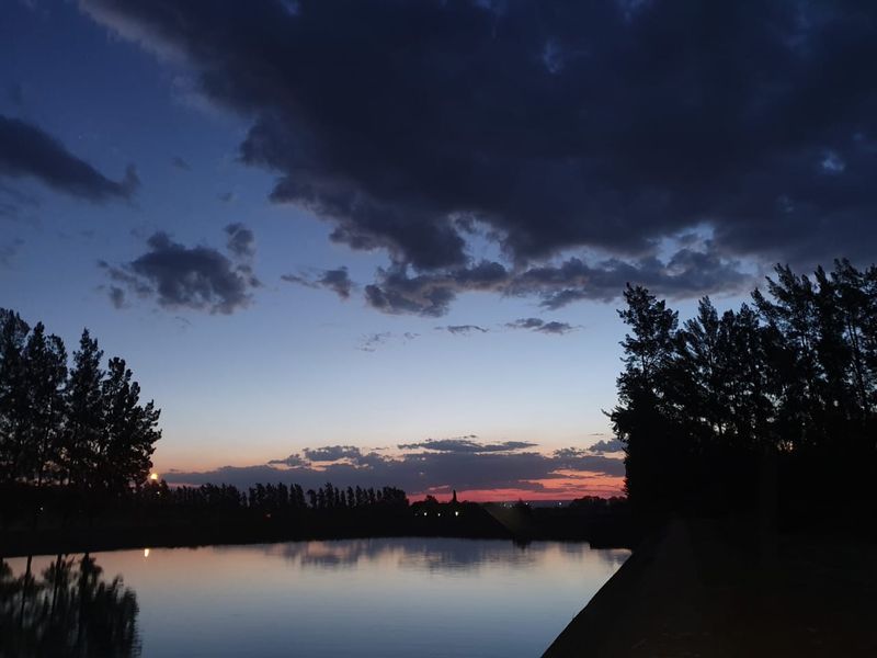 A scenic sunset view over a tranquil farm dam, showcasing the natural landscape and peaceful atmosphere of the property.