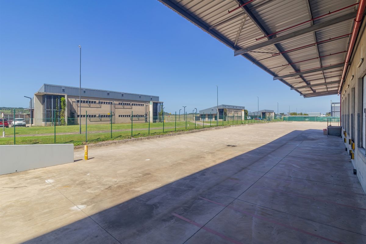 Spacious industrial loading yard featuring a large covered canopy, concrete hardstand, and secure perimeter fencing within a well-maintained business park.