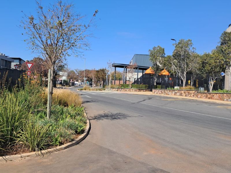 A view of the street approach leading to the office property, featuring landscaped verges and paved road infrastructure.
