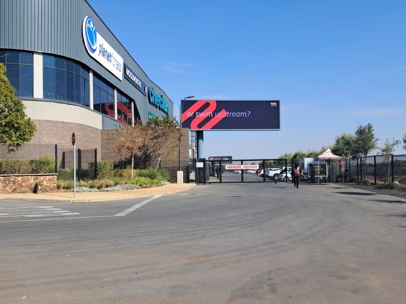 Exterior view of the office park entrance featuring modern facade cladding, paved driveway, and secure gated access.