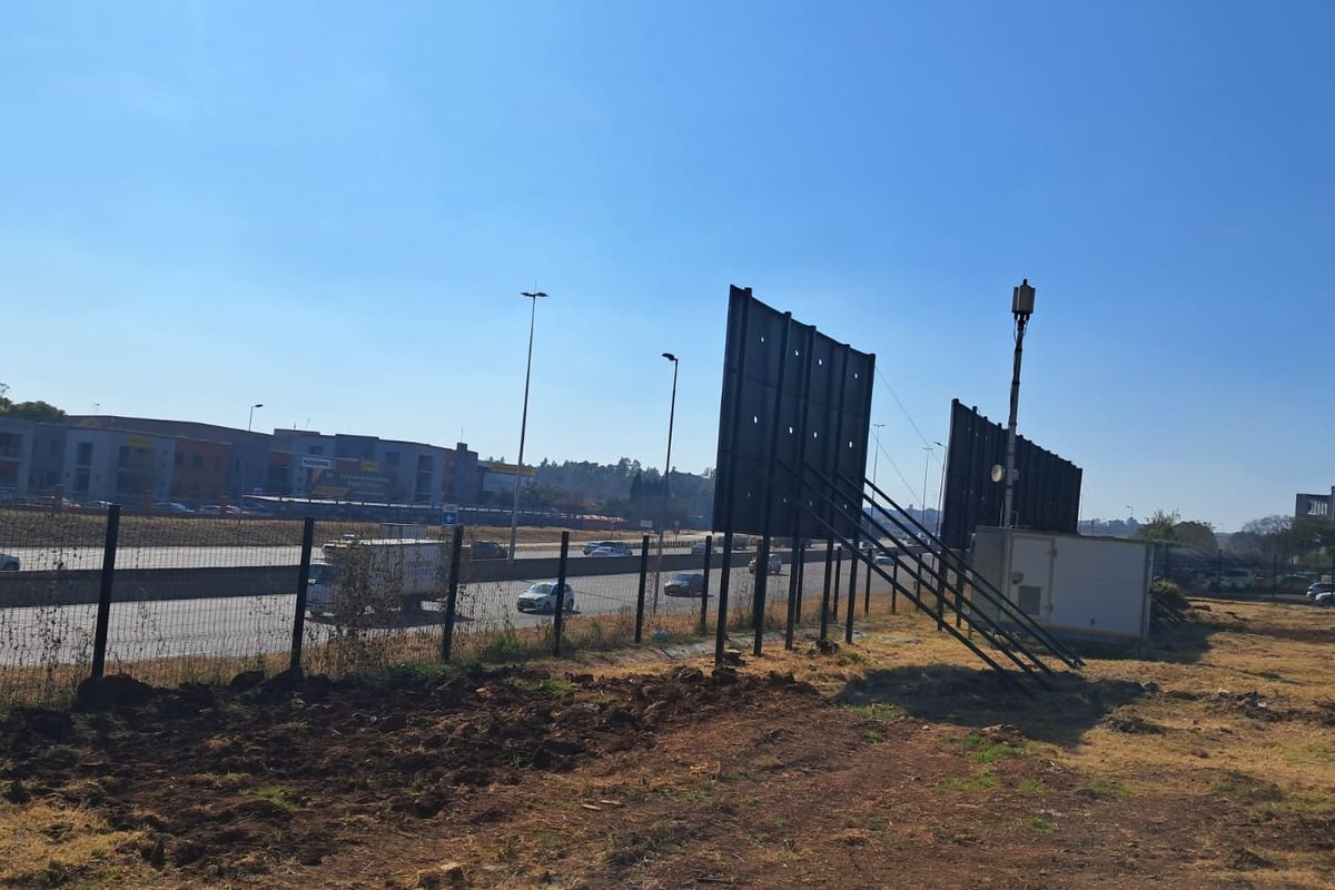 Exterior view of the property boundary featuring large advertising billboards and perimeter fencing adjacent to a major highway.