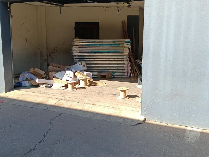 A functional industrial garage space featuring concrete flooring and masonry walls, currently used for storage.