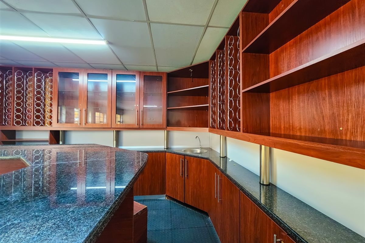 A functional office kitchenette featuring dark granite countertops, extensive built-in wooden cabinetry, and a small integrated sink.