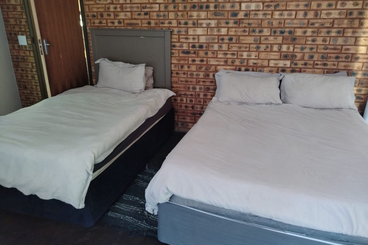 A bedroom featuring an exposed brick feature wall and neutral flooring.