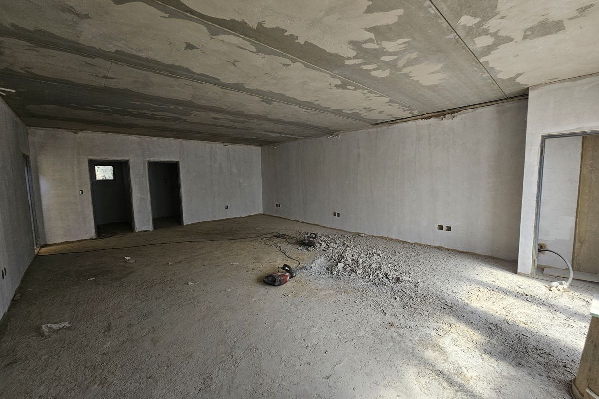 An open-plan industrial space currently under construction, featuring raw concrete ceilings, plastered walls, and unfinished flooring, suitable for custom fit-out.