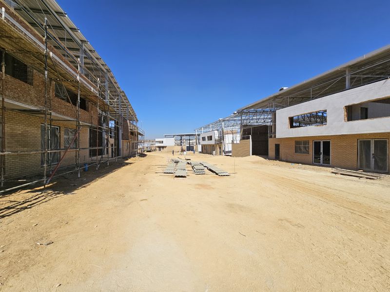 A wide-angle view of an industrial property under construction, featuring steel roof structures, brick facades, and ongoing site development.