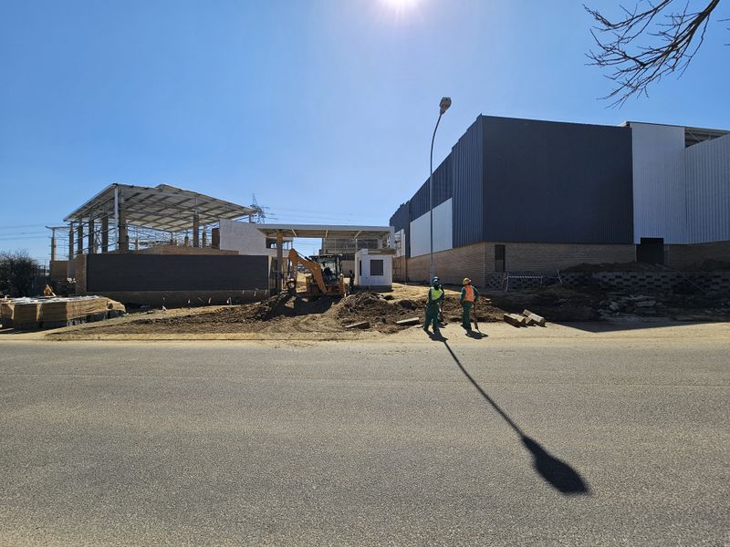 View of an industrial property currently under construction, featuring steel structural framing, metal cladding, and brickwork elements.