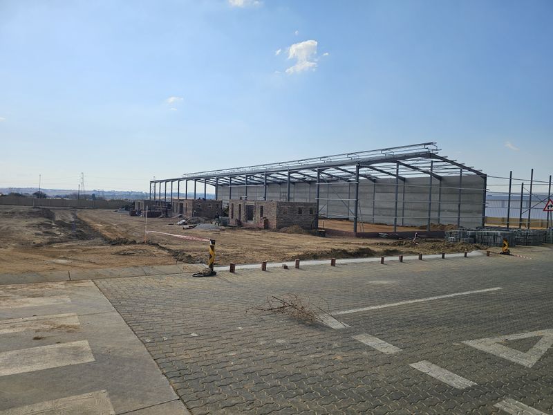 An industrial property under construction featuring a steel portal frame structure and precast concrete wall panels on a large site.