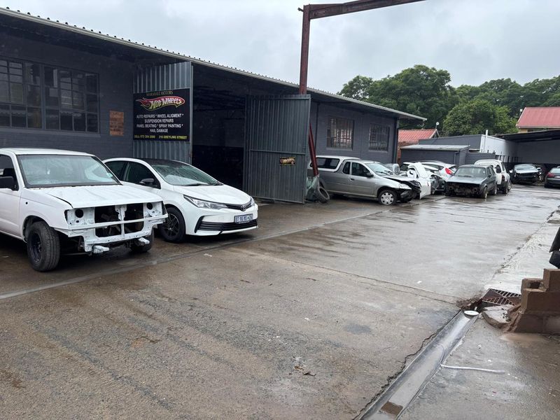 Industrial workshop facility featuring a large warehouse structure with steel sliding doors and an expansive concrete hardstand area.