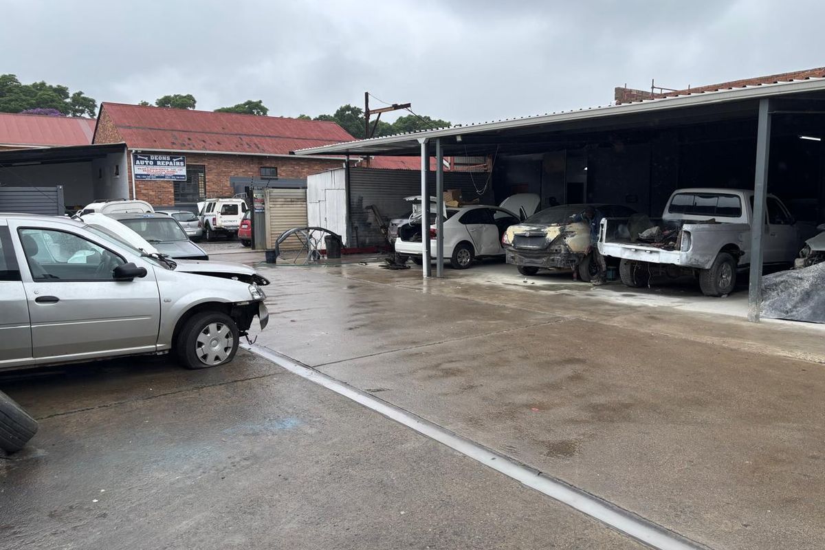 Industrial workshop area featuring a large concrete hardstand and a steel-framed covered workspace suitable for automotive repair operations.