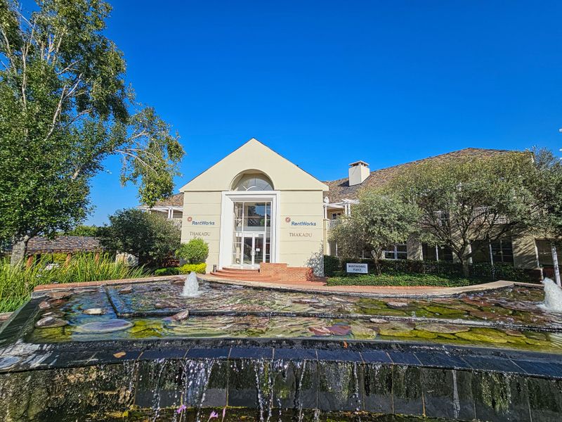 Front exterior view of the office building featuring a prominent water fountain, landscaped grounds, and a glass-fronted entrance.