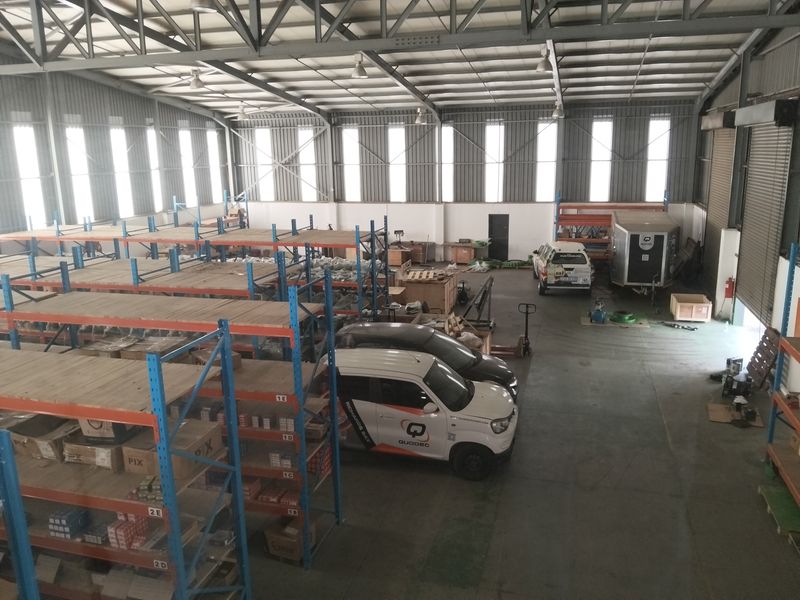 Spacious industrial warehouse featuring a high-clearance steel portal frame, corrugated metal walls, roller shutter access, and extensive built-in industrial racking systems.