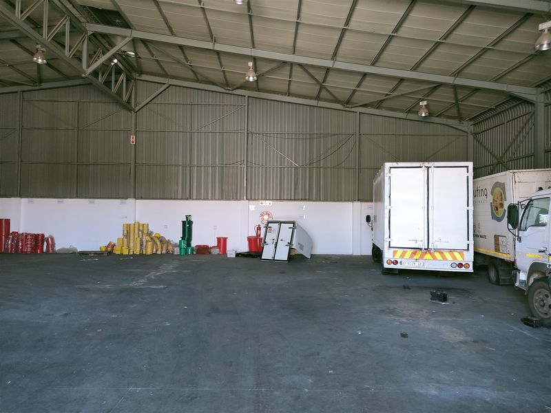 Spacious industrial warehouse unit featuring high ceilings, concrete flooring, and industrial lighting, suitable for storage or manufacturing operations.