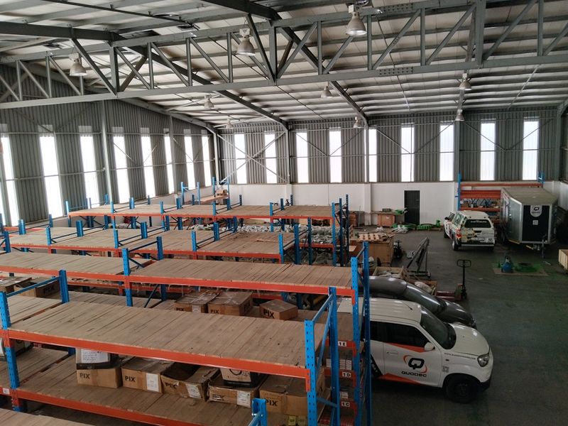 Spacious industrial warehouse featuring high-bay lighting, steel truss roofing, and extensive pallet racking systems on a durable concrete floor.