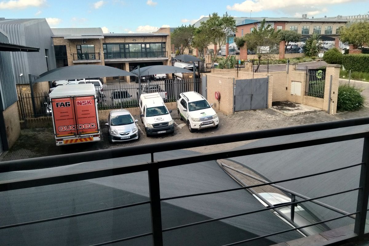 Elevated view of an industrial property courtyard featuring paved parking areas, shade cloth carports, and secure perimeter fencing.
