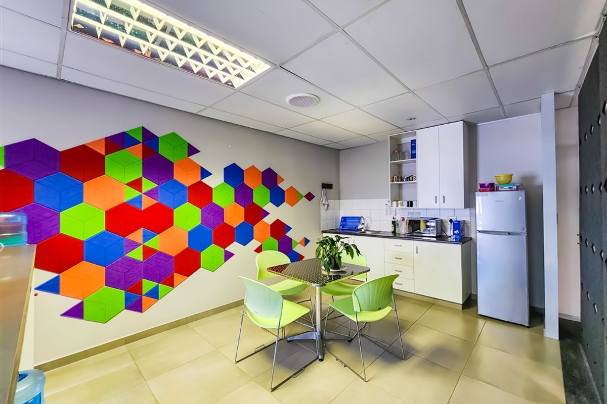 A functional office kitchenette featuring built-in cabinetry, tiled flooring, and a recessed ceiling light panel.