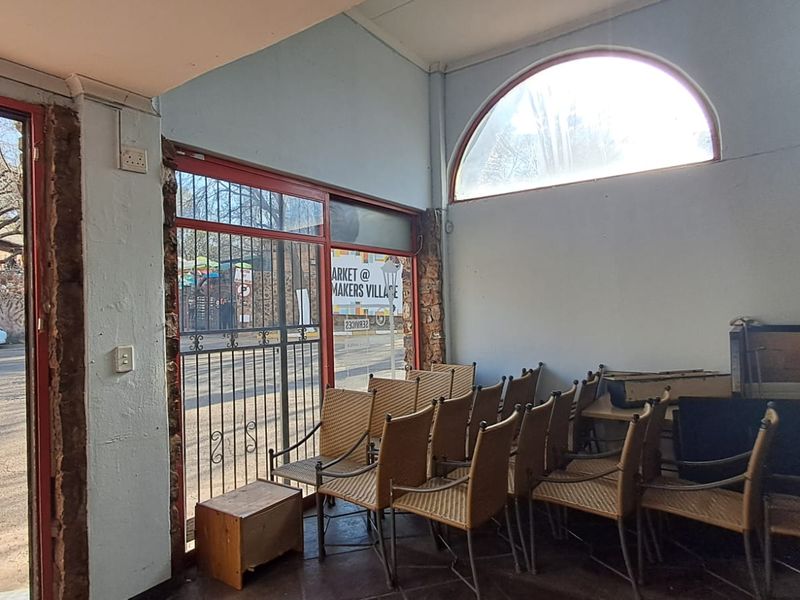 Entrance area featuring an arched window, security gate, and tiled flooring, showing signs of wear on the wall finishes.