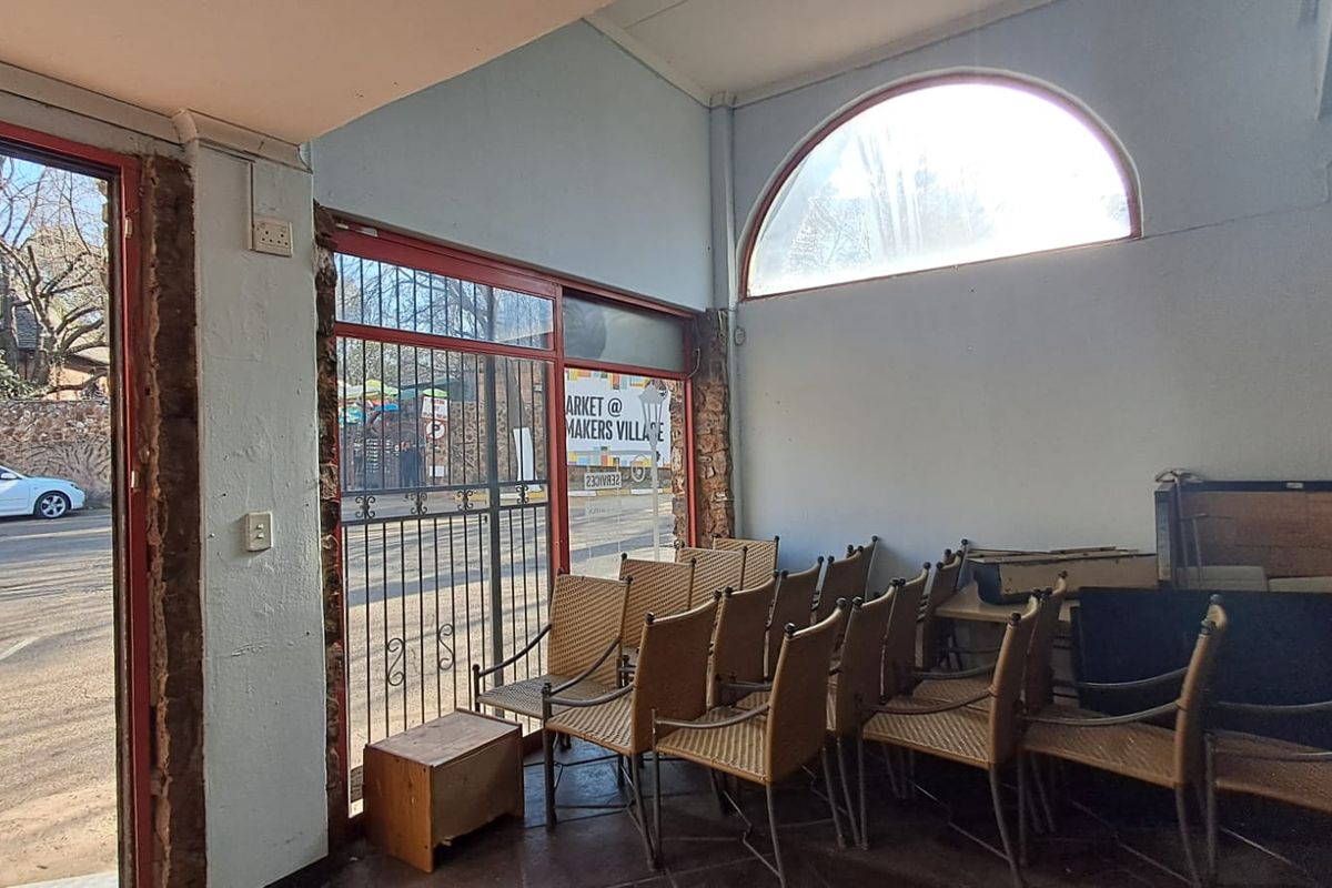 Entrance area featuring an arched window, security gate, and tiled flooring, showing signs of wear on the wall finishes.