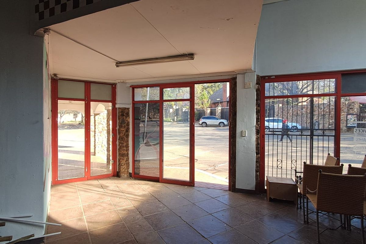 Entrance area featuring tiled flooring, red-framed glass doors, and security gates, providing direct access to the exterior parking area.
