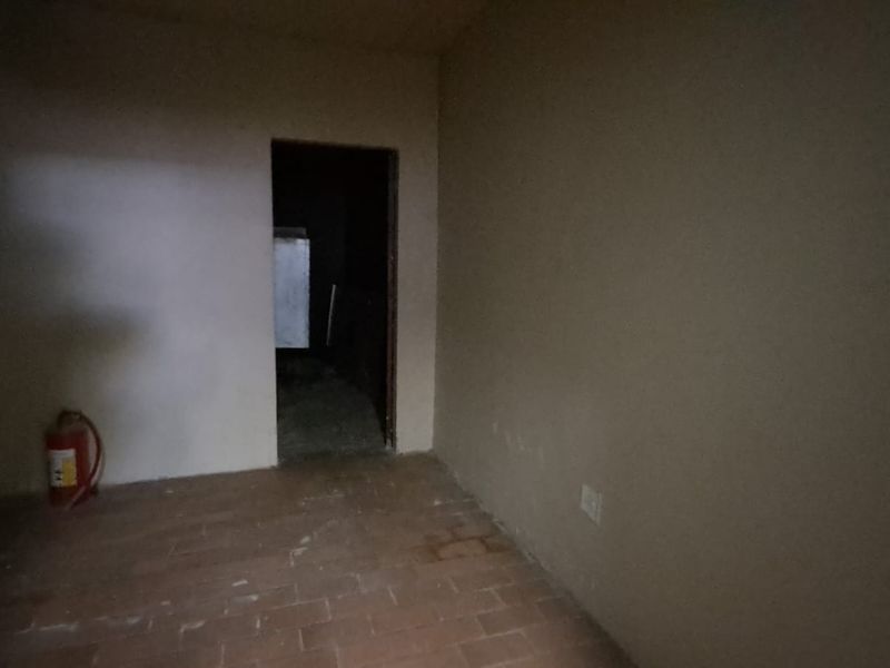 A sparse utility space featuring tiled flooring and a wall-mounted fire extinguisher, requiring cosmetic updates to improve the overall condition.