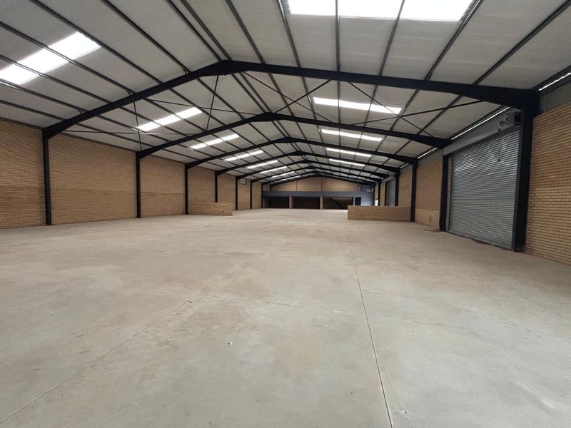 Spacious industrial warehouse featuring a steel portal frame, concrete flooring, roller shutter access, and ample natural light through integrated skylights.
