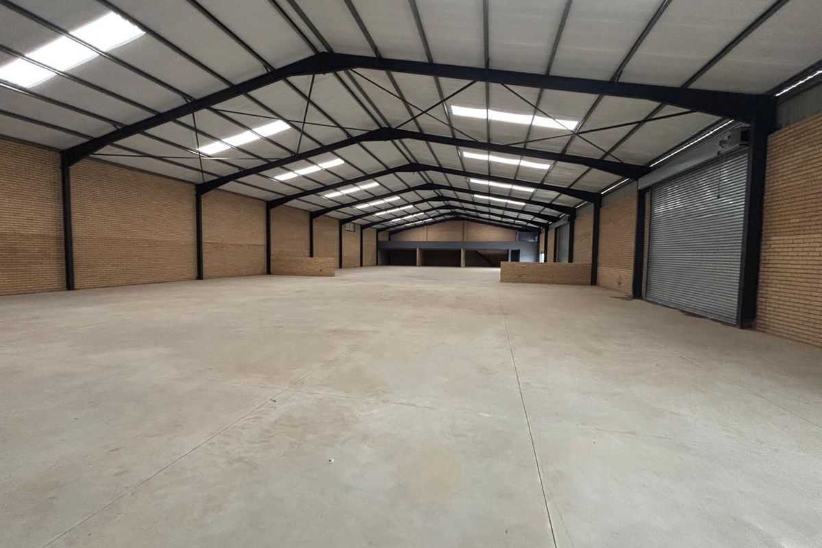 Spacious industrial warehouse featuring a steel portal frame, concrete flooring, roller shutter access, and ample natural light through integrated skylights.