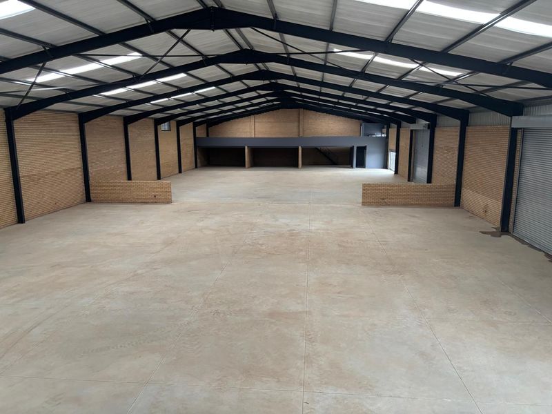 Spacious industrial warehouse featuring high ceilings with skylights, exposed steel portal frame, concrete flooring, and a mezzanine level for additional storage or office space.