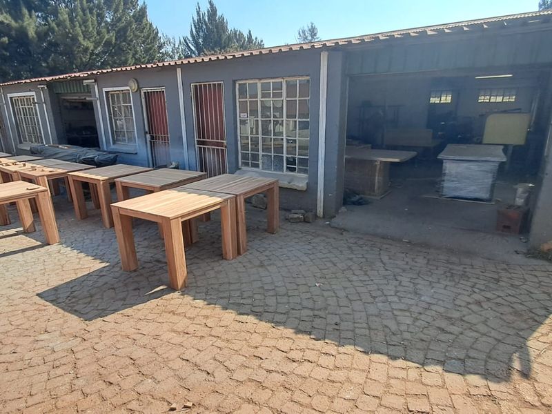 Industrial workshop exterior featuring a row of service bays, security gates, and cobblestone paving, suitable for manufacturing or storage operations.