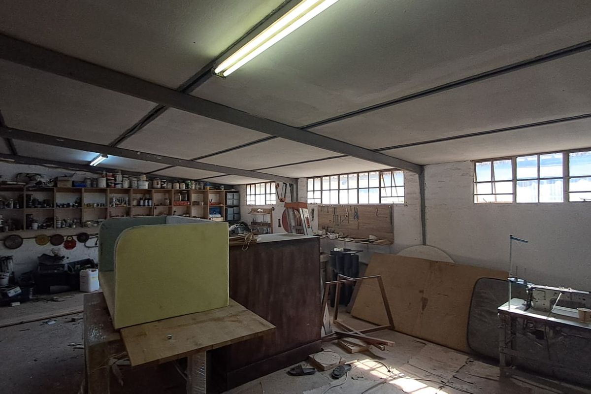 Spacious industrial utility area featuring exposed steel ceiling beams, built-in timber shelving, and multiple windows providing natural light.