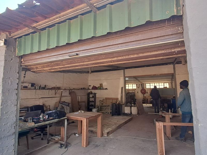Industrial garage space featuring exposed brick walls, concrete flooring, and a large roller shutter door, suitable for workshop or storage use.