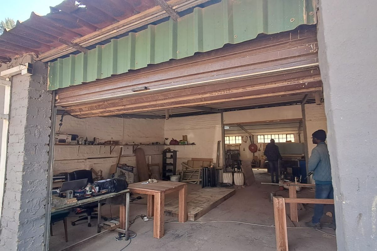 Industrial garage space featuring exposed brick walls, concrete flooring, and a large roller shutter door, suitable for workshop or storage use.