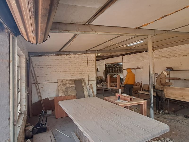 Industrial workshop space featuring exposed steel beams, painted brick walls, and an open-plan layout suitable for manufacturing or storage operations.