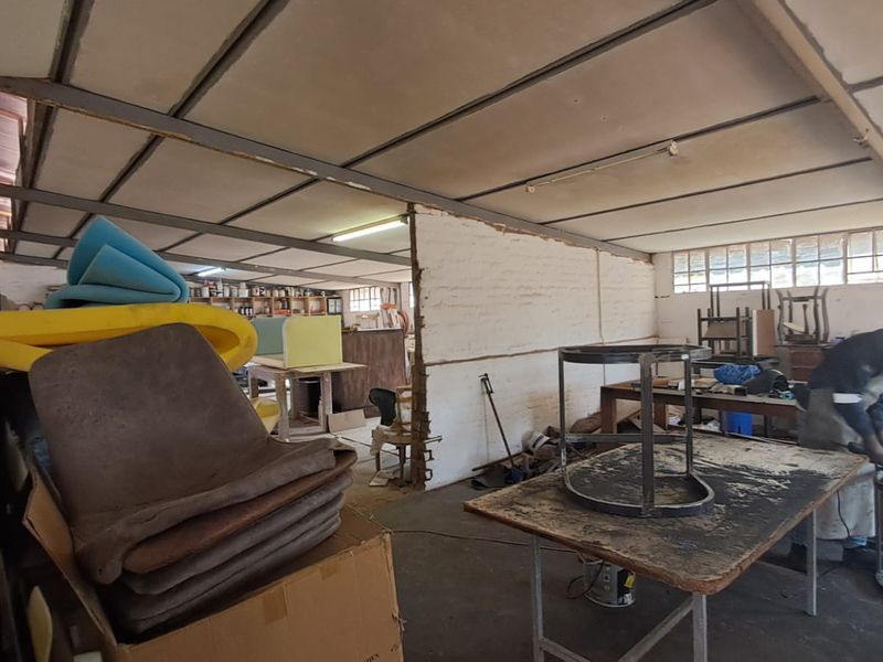 Industrial workshop space featuring exposed ceiling structure, masonry partition walls, and functional lighting, suitable for manufacturing or storage operations.