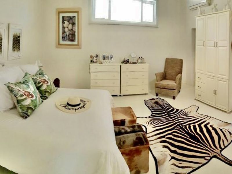 Spacious bedroom featuring neutral finishes, built-in wardrobe, air conditioning, and direct access to an en-suite bathroom.