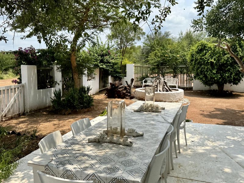 Outdoor patio area featuring a concrete floor, built-in fire pit, and surrounding garden wall, providing a functional space for outdoor entertaining on the farm.