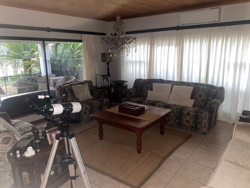 A comfortable living room featuring a timber ceiling, tiled flooring, and a split-system air conditioner, with large sliding doors providing access to the patio.